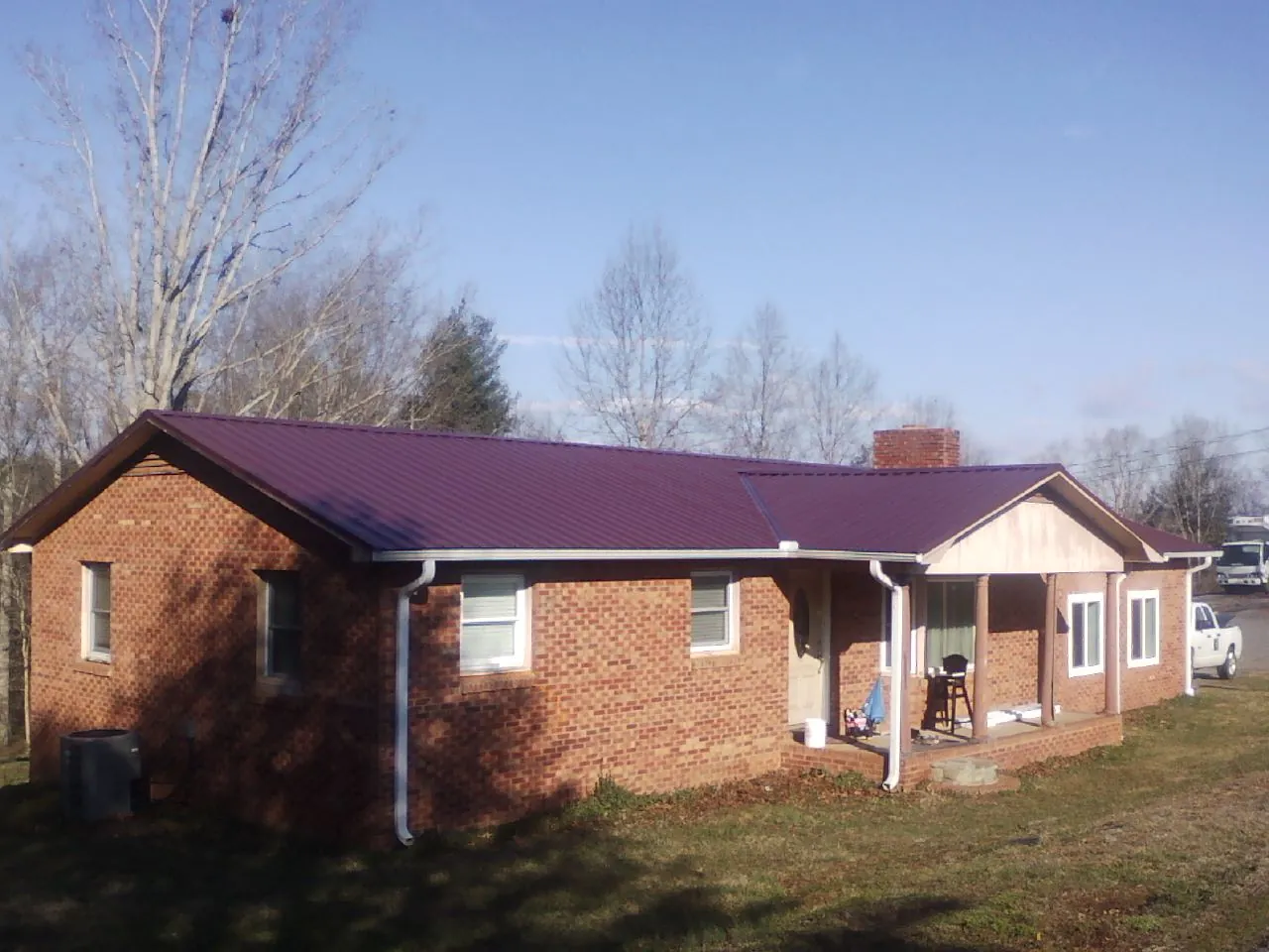 Burgundy metal roof on a brick ranch home with a new addition in Hayesville