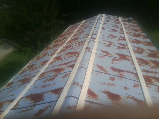 Rusted metal roof panels with new wood purlins before replacement — Storm Damage Roof Repair in Hayesville by Roofing Brothers
