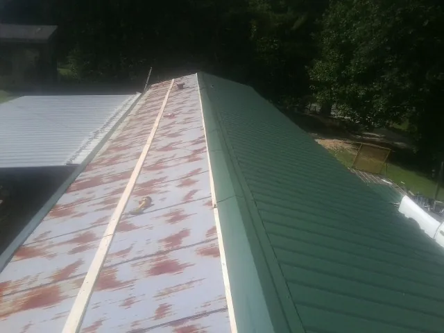 Old rusted panels beside newly installed green metal roofing — Wind Damage Roof Repair by Roofing Brothers in Hayesville