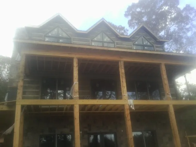 Dormers and porch framing on a large log home under construction — Roof Coating work by our crew in Hayesville