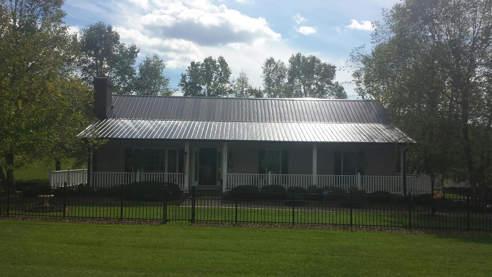 Gray metal roof on a brick ranch with a full width front porch — Gutter Guard Installation work by our crew in Hayesville
