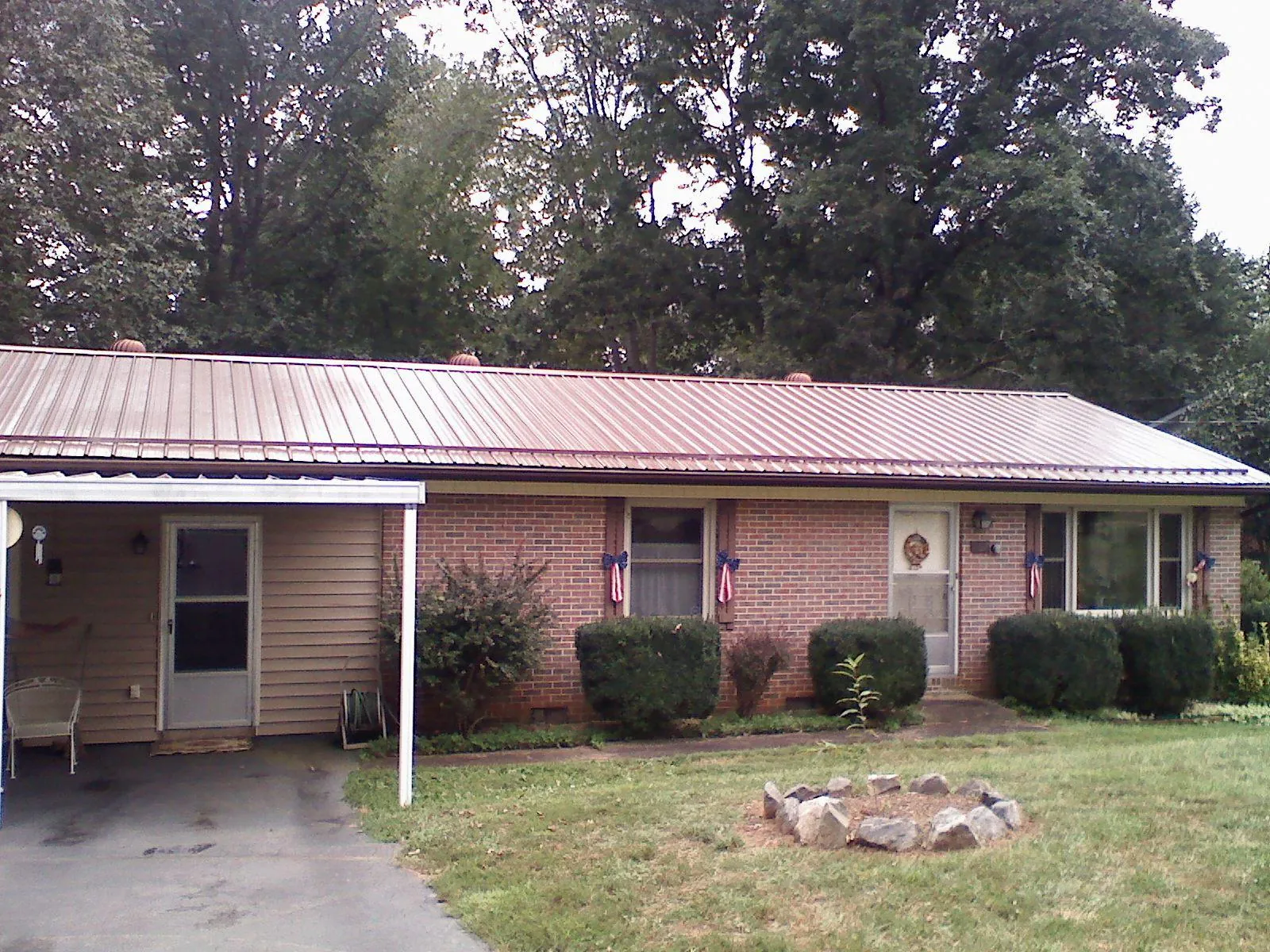 Bronze metal roof and carport on a brick ranch home — Roof Repair work by our crew in Hayesville