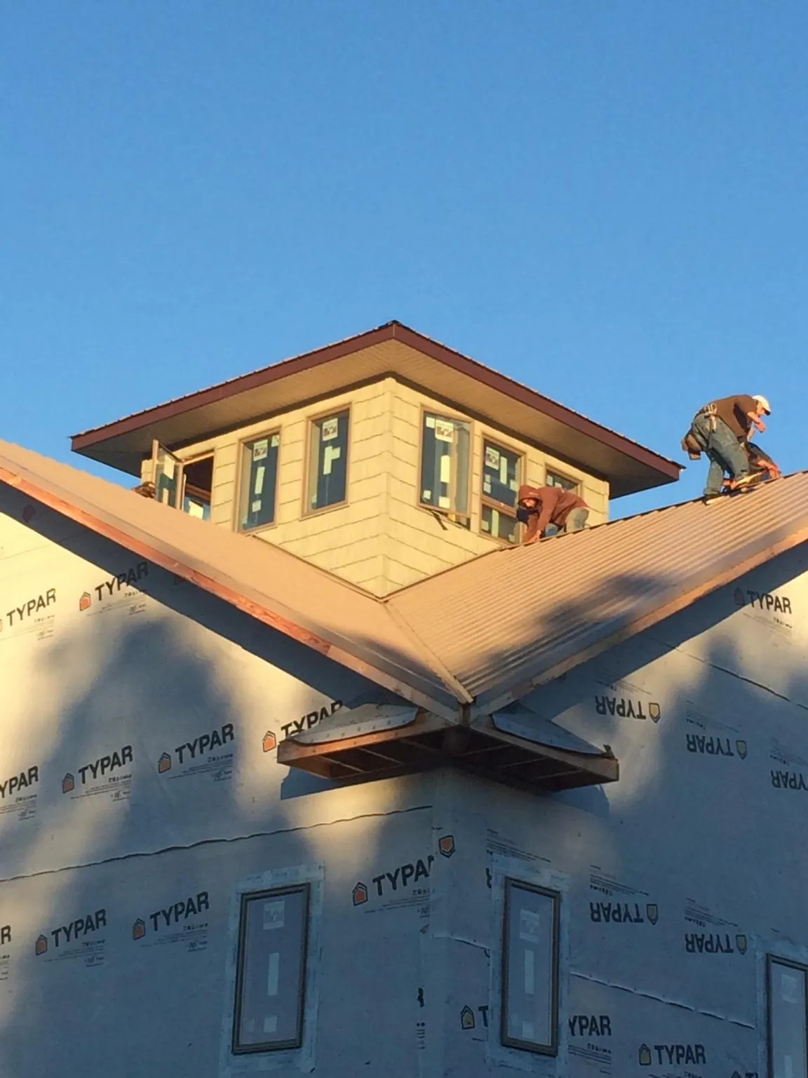 Roofers working around a rooftop cupola on a new metal roof at sunset — Roof Waterproofing in Hayesville by Roofing Brothers